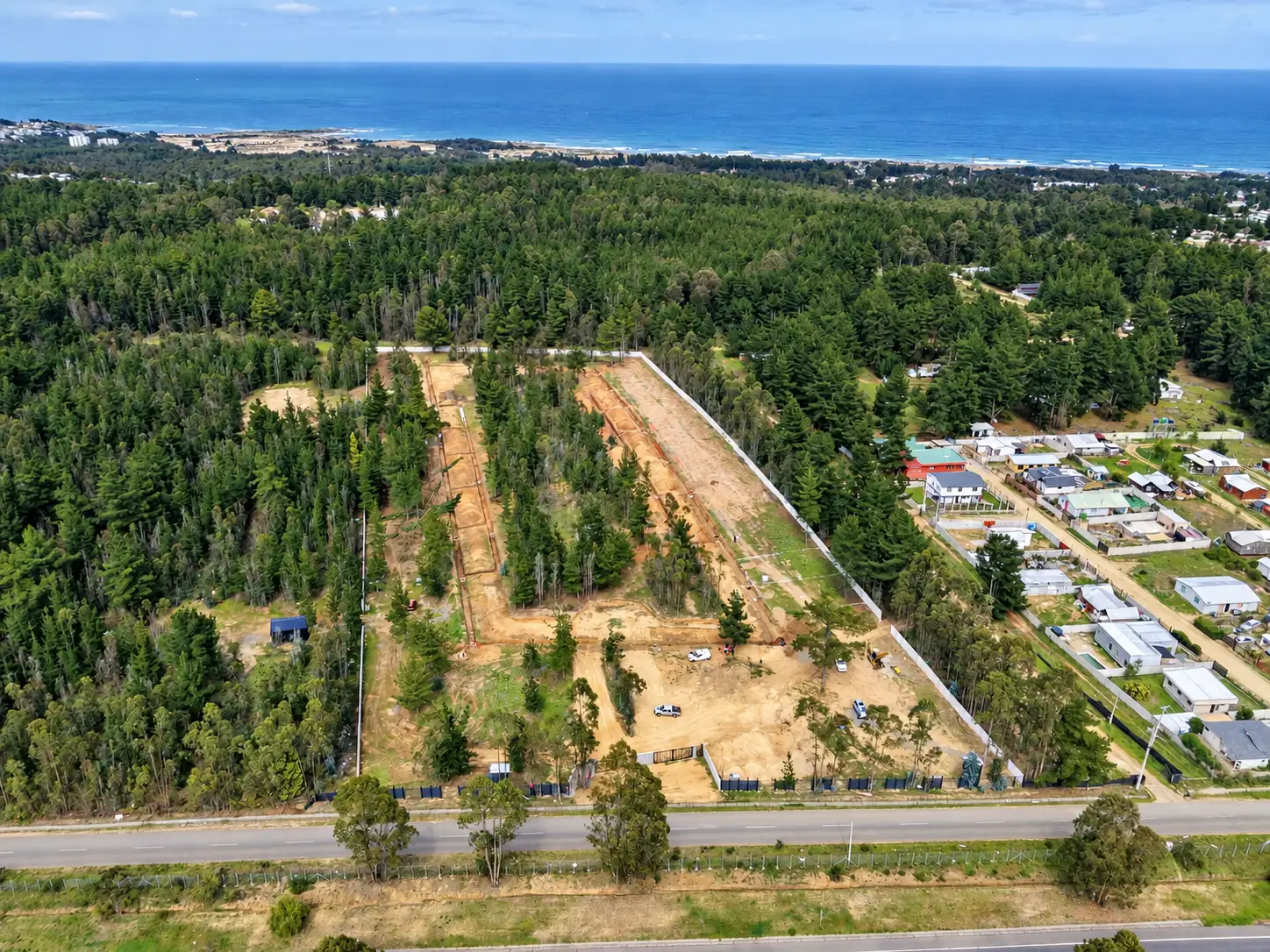 Vista aérea de un terreno en urbanización entre el bosque, cerca de la costa